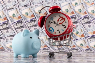 Domuz kumbarası, süpermarket alışveriş arabası ve çalar saat. 100 dolarlık banknot.