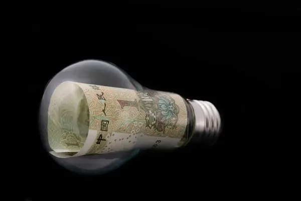 stock image Chinese yuan 1 banknote in a regular incandescent lamp on a black background