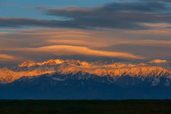 stock image Picturesque lenticular clouds over the mountain peaks of the Zili Alatu in the Almaty region (Kazakhstan) on a spring evening