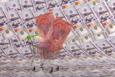 Bir süpermarketten alınmış minyatür bir alışveriş arabasında 5000 tenge fatura 100 Amerikan dolarının arka planında.