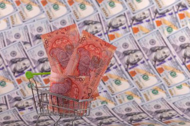Bir süpermarketten alınmış minyatür bir alışveriş arabasında 5000 tenge fatura 100 Amerikan dolarının arka planında.