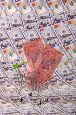 Bir süpermarketten alınmış minyatür bir alışveriş arabasında 5000 tenge fatura 100 Amerikan dolarının arka planında.