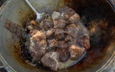 Büyük et parçaları büyük bir kazanda kızarır.