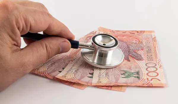 Elindeki steteskopun başı 5000 Kazakistan banknotuna bağlıdır..