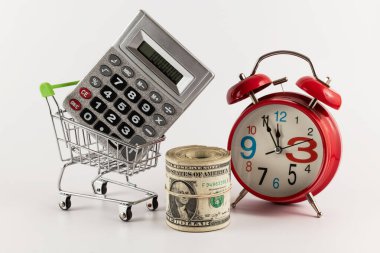 Bir yığın 1 dolarlık banknot, bir hesap makinesi ve minyatür süpermarket alışveriş arabası.