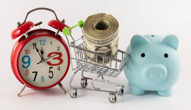 1 dolarlık banknotlar, çalar saat, kumbara ve süpermarket alışveriş arabası.