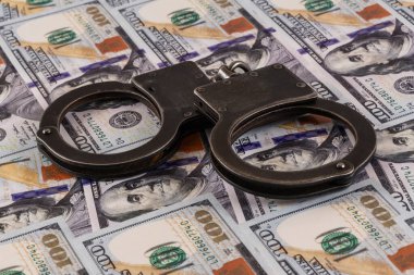 100 dolarlık banknotların arka planında kelepçeler var.