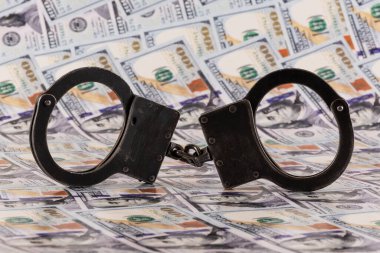 100 dolarlık banknotların arka planında kelepçeler var.