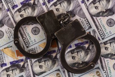 100 dolarlık banknotların arka planında kelepçeler var.