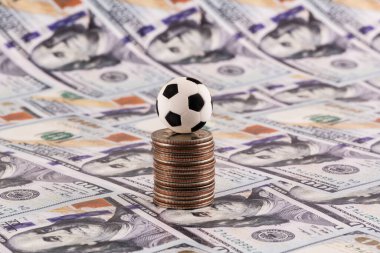 Arkasında 100 dolarlık banknotlar olan minyatür futbol topu.