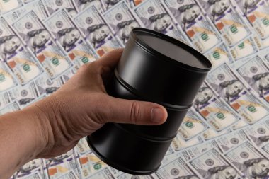 Arka planda 100 dolarlık banknotlar olan metal yağ fıçısı.