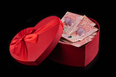5000 Kazakistanlı banknotlar kırmızı bir hediye kutusunda insan kalbinin sembolü olarak duruyor.