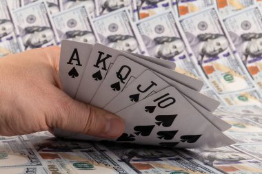 Maça floşu, pokerdeki en güçlü el, arka planda 100 dolarlık banknotlara karşı.