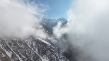 Bir kış günü, Kazak şehri Almaty yakınlarındaki Trans-Ili Alatau dağlarında bulutların arasından manzaralı bir vadiye bakın.