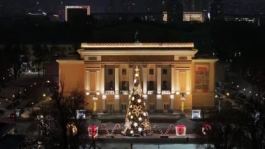 Almaty, Kazakistan, 01.09.2025. Almaty 'nin merkezinde yer alan Opera ve Bale Tiyatrosu' nun bir kuadkopterinden bir kış akşamında Noel ağacı ile görüntülenir.
