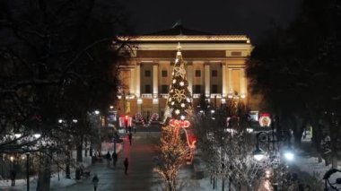 Almaty, Kazakistan, 01.09.2025. Almaty 'nin merkezinde yer alan Opera ve Bale Tiyatrosu' nun bir kuadkopterinden bir kış akşamında Noel ağacı ile görüntülenir.