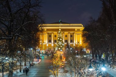 Almaty, Kazakistan, 01.09.2025. Almaty 'nin merkezinde yer alan Opera ve Bale Tiyatrosu' nun bir kuadkopterinden bir kış akşamında Noel ağacı ile görüntülenir.