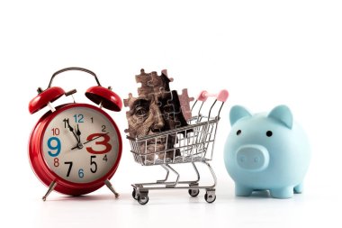 Benjamin Franklin 'in yapboz portresi ve beyaz arka planda 100 dolarlık minyatür süpermarket alışveriş arabası.