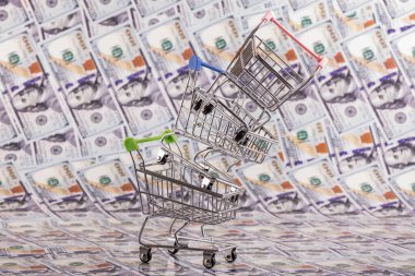 Bir süpermarketten gelen boş alışveriş arabaları piramidi 100 Amerikan dolarının arka planına karşı.