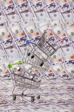 Bir süpermarketten gelen boş alışveriş arabaları piramidi 100 Amerikan dolarının arka planına karşı.