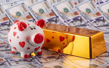 Domuz kumbarası ve 999 altın külçe 100 dolarlık banknotlara karşı.