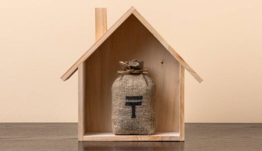 Kazakistan 'da sembolik ahşap bir ev ve içinde Kazak para birimi sembolü olan bir para çantası olan gayrimenkul konulu kavramsal bir komplo.