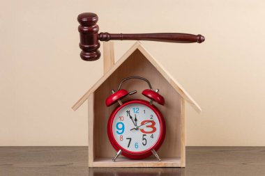 Sembolik ahşap ev, çalar saat ve yargıç tokmağı.