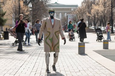 Almaty, Kazakistan, 03.21.2025. Bir bahar günü Kazak şehrinin caddesinde geleneksel Kazak kıyafetleri içinde bir android robot.