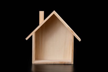 Ahşap ev modeli siyah arka planda izole edilmiş. Emlak kavramı