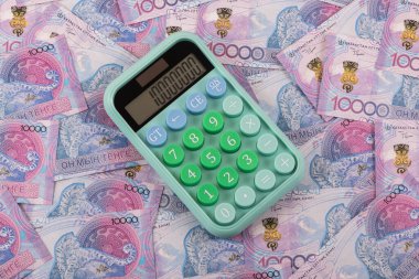 Hesap makinesi ve 10,000 Kazakistan tenge faturası.