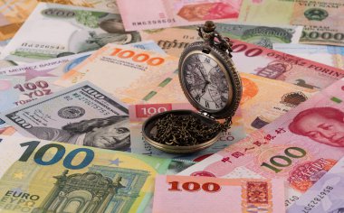 Dünyanın farklı ülkelerinden gelen çeşitli banknotların arka planında zincirli cep saati
