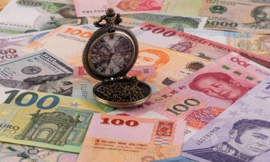 Dünyanın farklı ülkelerinden gelen çeşitli banknotların arka planında zincirli cep saati