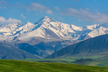 Güneydoğu Kazakistan 'ın Almaty bölgesinde bir bahar günü, bir dağ platosunun üzerinde kar ve buzla kaplı pitoresk bir zirve.