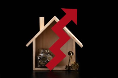 Sembolik ahşap ev, 100 ve 200 Kazakistan parası, altın anahtar ve siyah arkaplanda kırmızı ok.