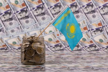 100 ve 200 Kazakistan paralı cam kavanoz ve 100 Amerikan dolarının arka planında Kazakistan bayrağı.