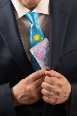 Kazakistan bayrağının bir parçasıyla takım elbiseli ve kravatlı bir adamın 10 bin Kazak çadırını elinde tutarken.