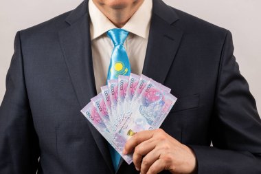Kazakistan bayrağının bir parçasıyla takım elbiseli ve kravatlı bir adamın 10 bin Kazak çadırını elinde tutarken.