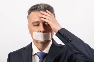 İş elbisesi giymiş, ağzı bandajla kaplanmış bir adamın yüzünü yakından çek.
