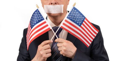 Ağzı bandaj ve Amerikan bayraklarıyla kaplı iş elbisesi giymiş bir adamın yüzünü yakından çek.