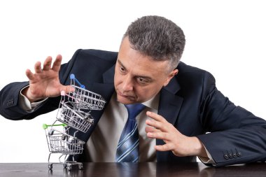 Takım elbiseli orta yaşlı bir adam ve boş minyatür market arabaları piramidi.