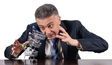 Takım elbiseli orta yaşlı bir adam ve boş minyatür market arabaları piramidi.