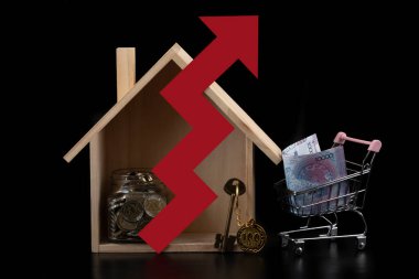 Sembolik ahşap ev, 10000 tenge banknot, 100 ve 200 Kazakistan parası, altın anahtar ve siyah arkaplanda kırmızı ok.