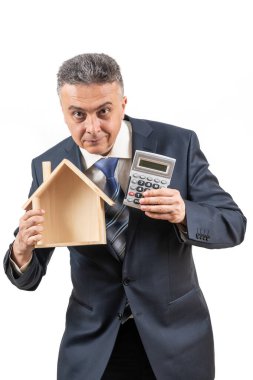 İş elbisesi, hesap makinesi ve sembolik ahşap ev giyen orta yaşlı bir adam.
