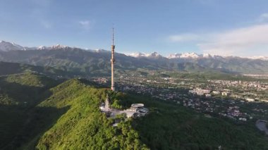 Kok Tobe Dağı (Mavi Tepe) ve ünlü TV kulesi Kazak şehri Almaty 'deki Zailiyskiy Alatau dağ sırasının arka planına karşı bir bahar sabahı erken saatlerde