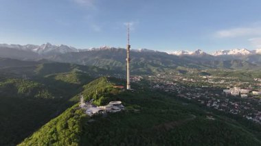 Kok Tobe Dağı (Mavi Tepe) ve ünlü TV kulesi Kazak şehri Almaty 'deki Zailiyskiy Alatau dağ sırasının arka planına karşı bir bahar sabahı erken saatlerde