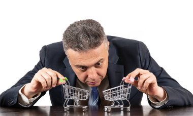 Takım elbiseli orta yaşlı bir adam ve iki boş süpermarket arabası.