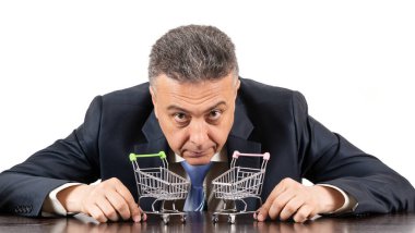 Takım elbiseli orta yaşlı bir adam ve iki boş süpermarket arabası.