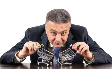 Takım elbiseli orta yaşlı bir adam ve iki boş süpermarket arabası.