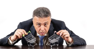 Takım elbiseli orta yaşlı bir adam ve iki boş süpermarket arabası.