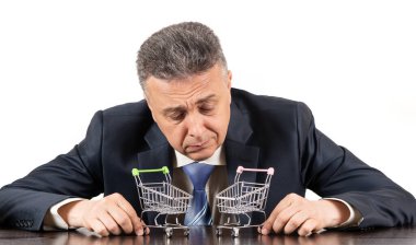 Takım elbiseli orta yaşlı bir adam ve iki boş süpermarket arabası.